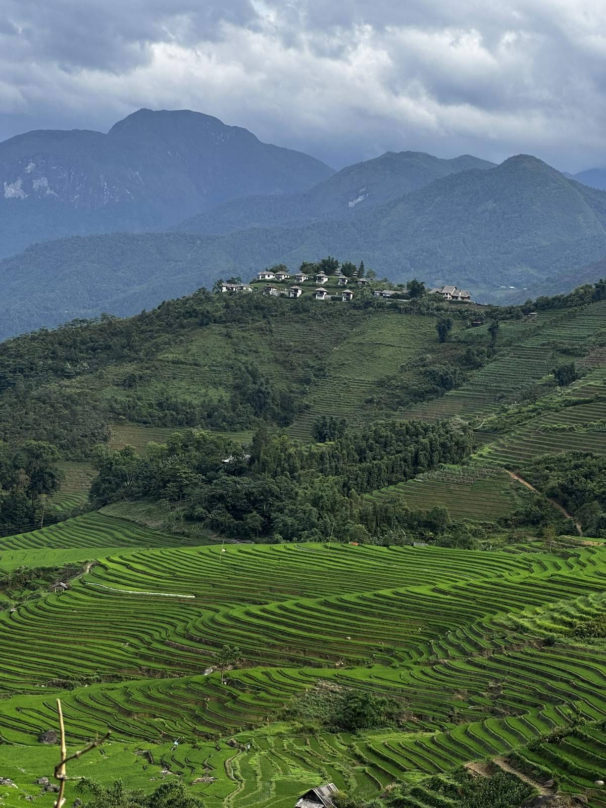 Hilltop village surrounded by terraces under storm clouds near Sapa