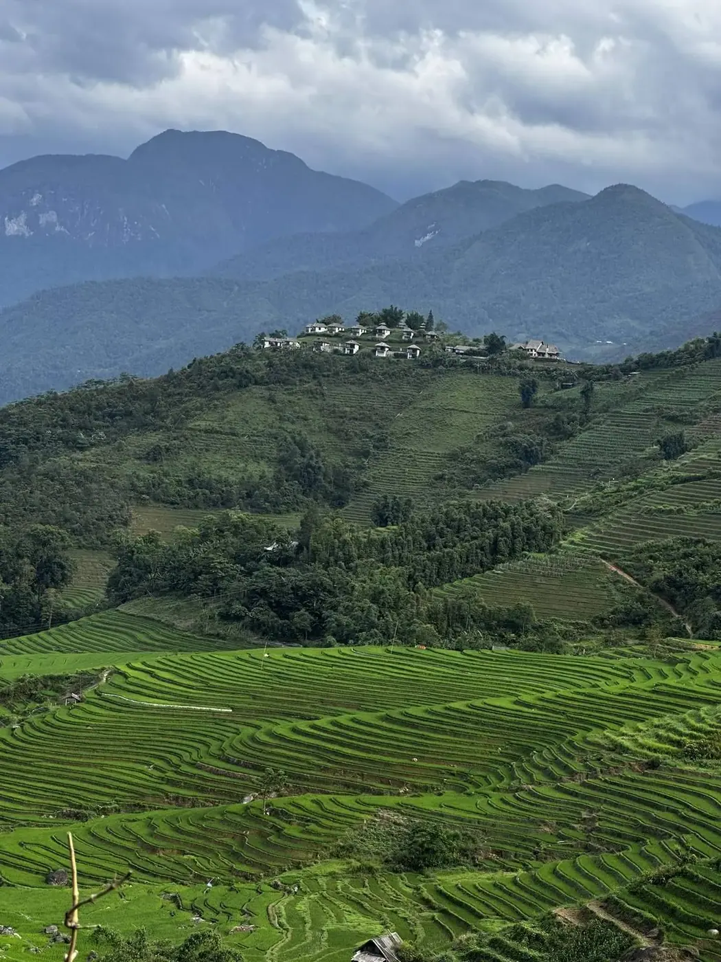 Hilltop village surrounded by terraces under storm clouds near Sapa