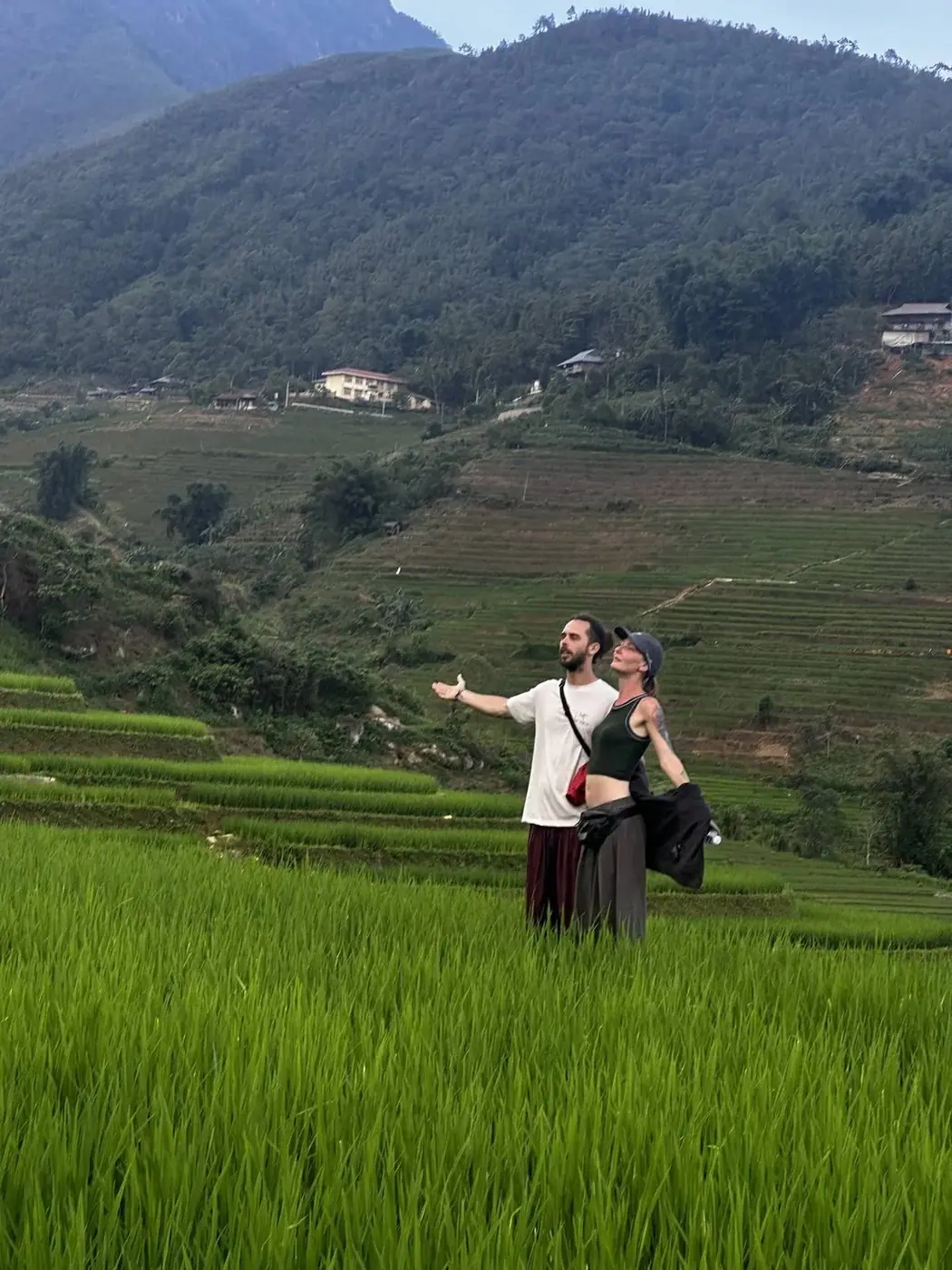 Travelers standing in a rice paddy near a Vietnamese hillside village
