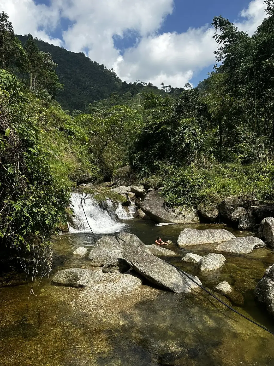 Small waterfall cascading through a forested stream in the mountains of northern Vietnam