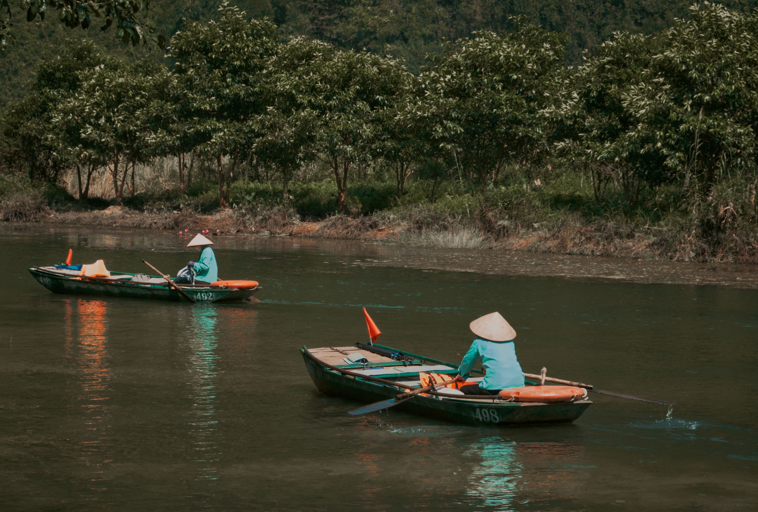 Solo boatwoman rowing a wooden sampan on the Tam Coc river