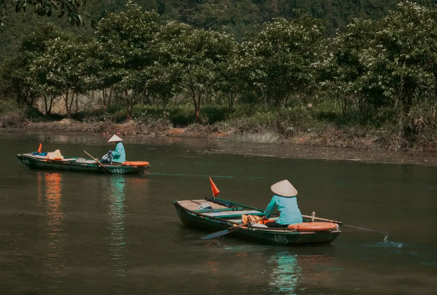 Solo boatwoman rowing a wooden sampan on the Tam Coc river