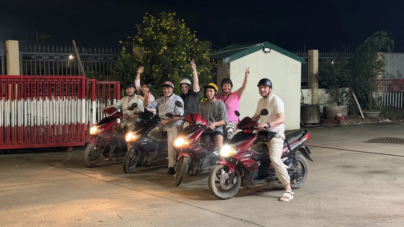 Tour group in helmets posing on scooters at night before a ride
