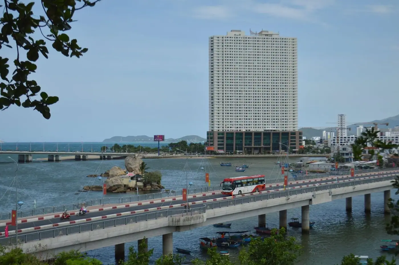 A coach bus crossing a bridge in a coastal Vietnamese city