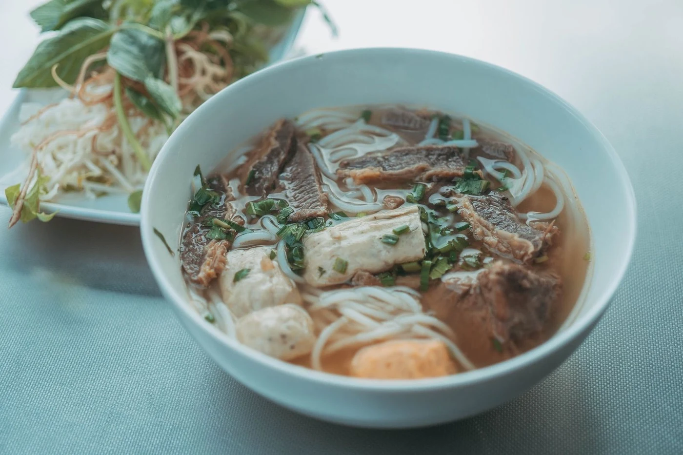 Bowl of pho bo noodle soup with beef and fresh herbs