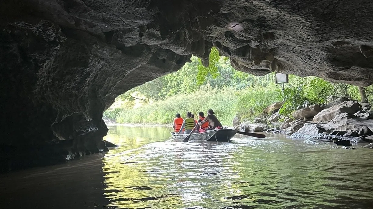 Rowing boat with tourists leaving a limestone cave tunnel in Ninh Binh