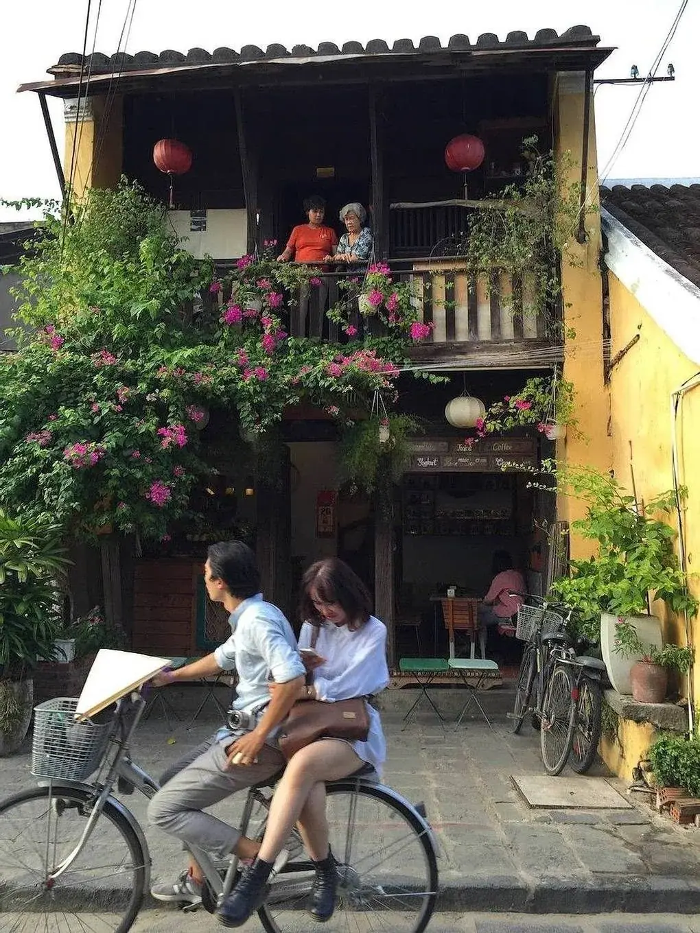Cyclists riding through a narrow street in Hoi An old town