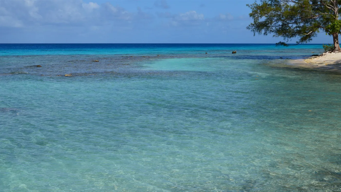 Clear shallow lagoon water lapping a sandy shoreline with no waves