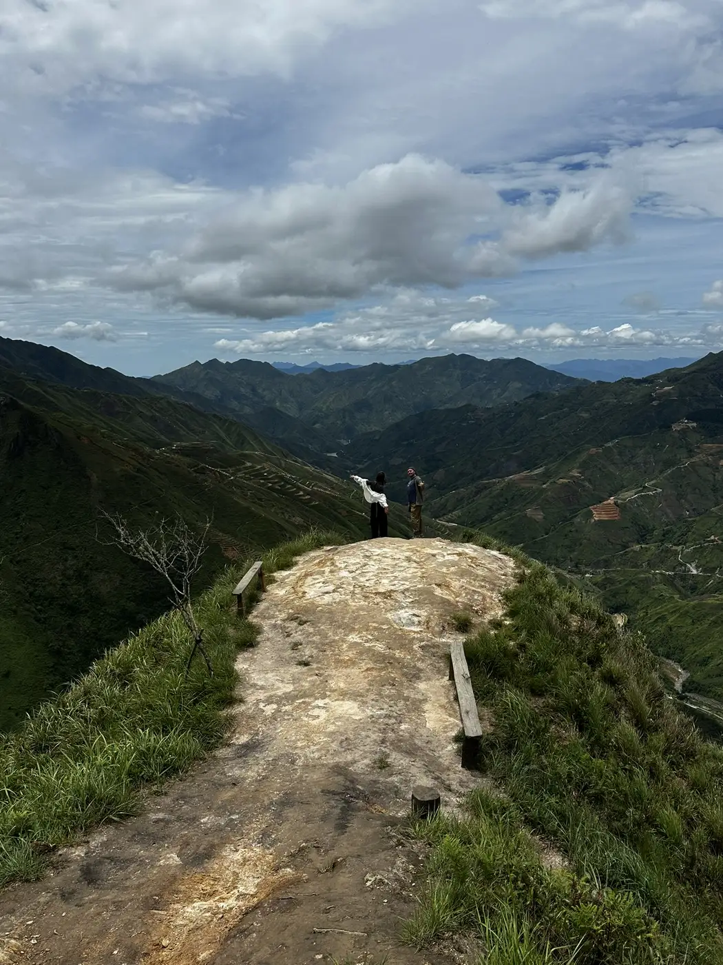 Two hikers admire a wide mountain valley view in northern Vietnam