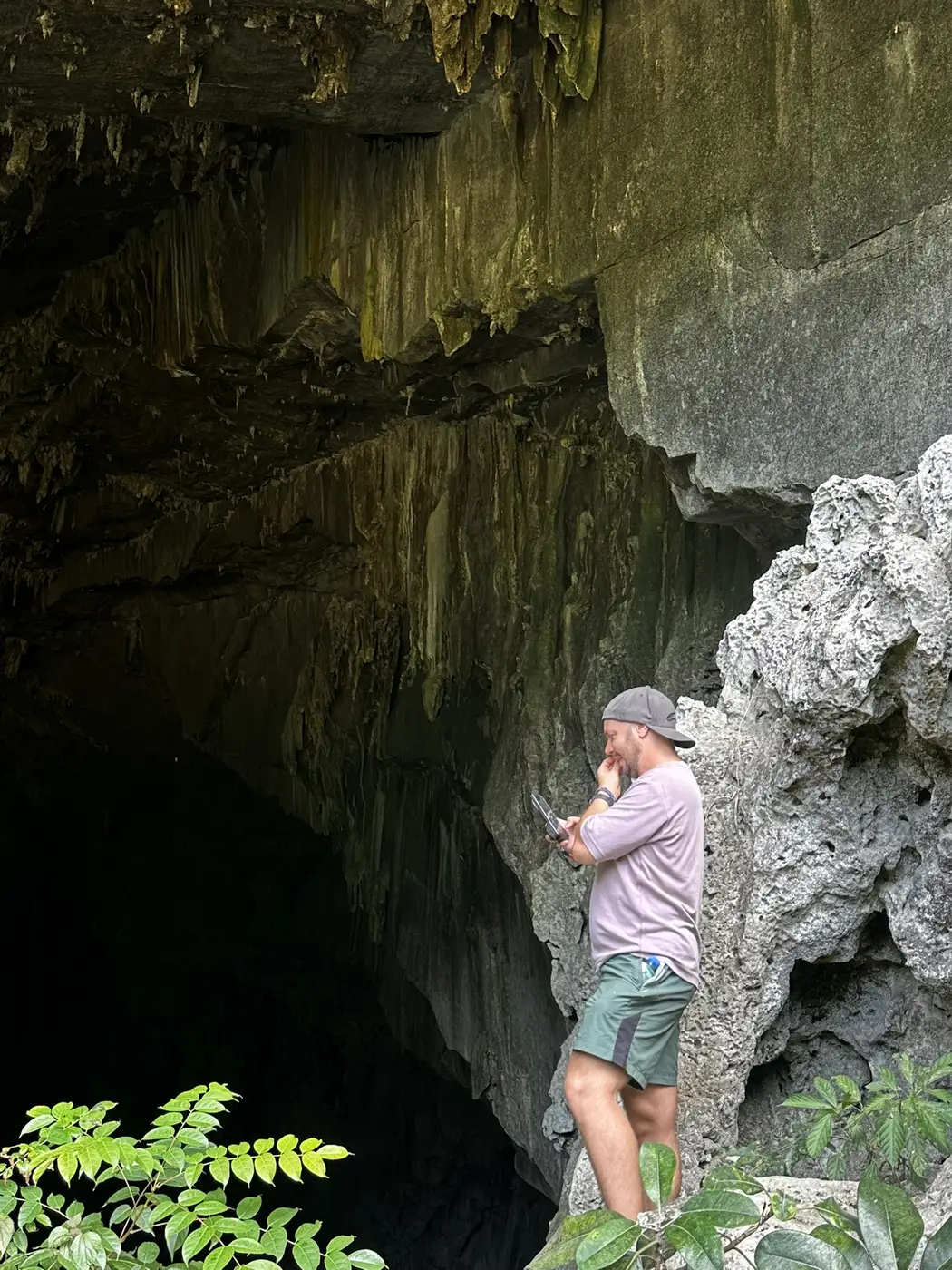 Traveler standing at the dark entrance of a Vietnamese limestone cave