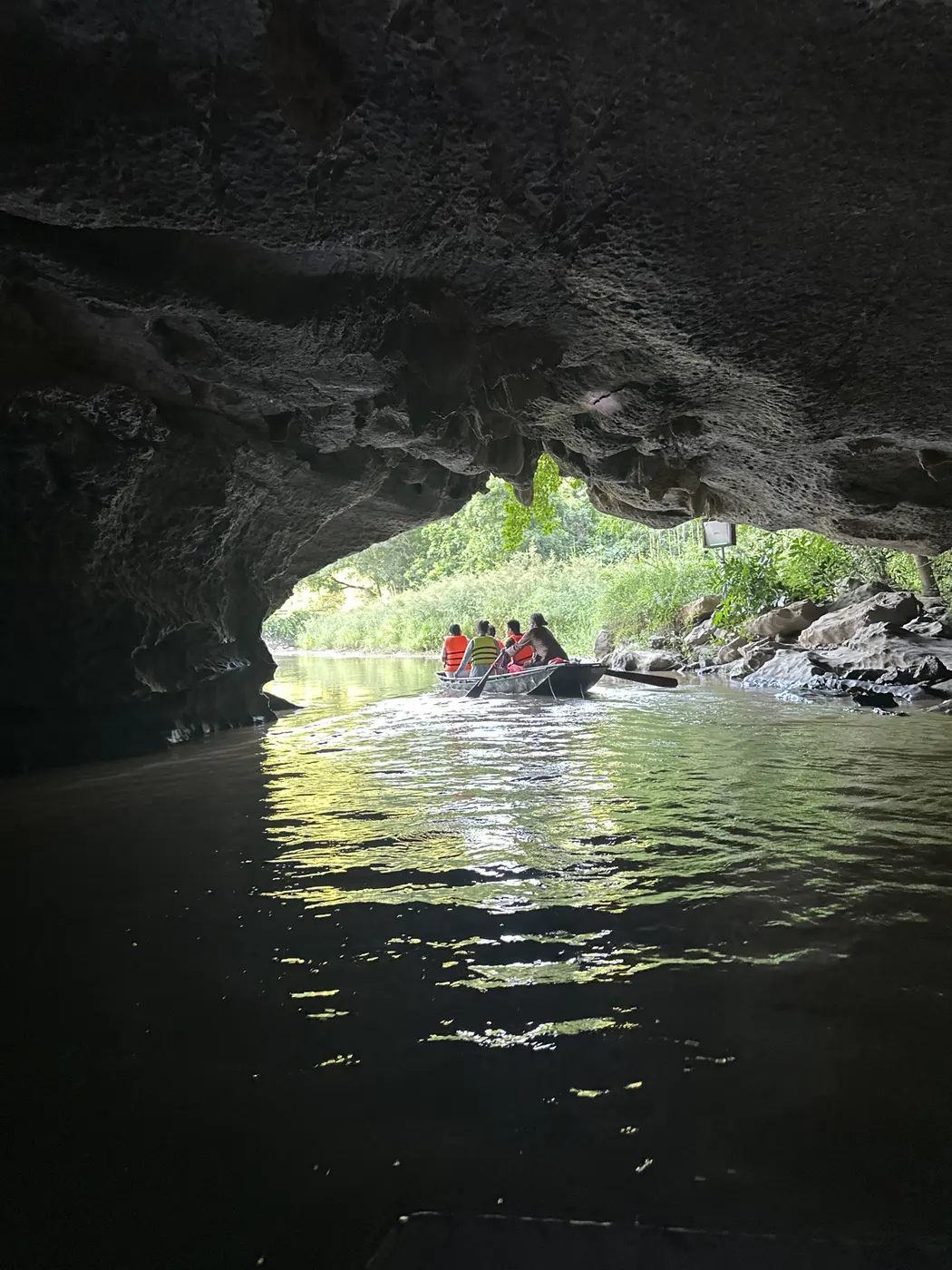Boat emerging from a cave grotto at Trang An toward the light