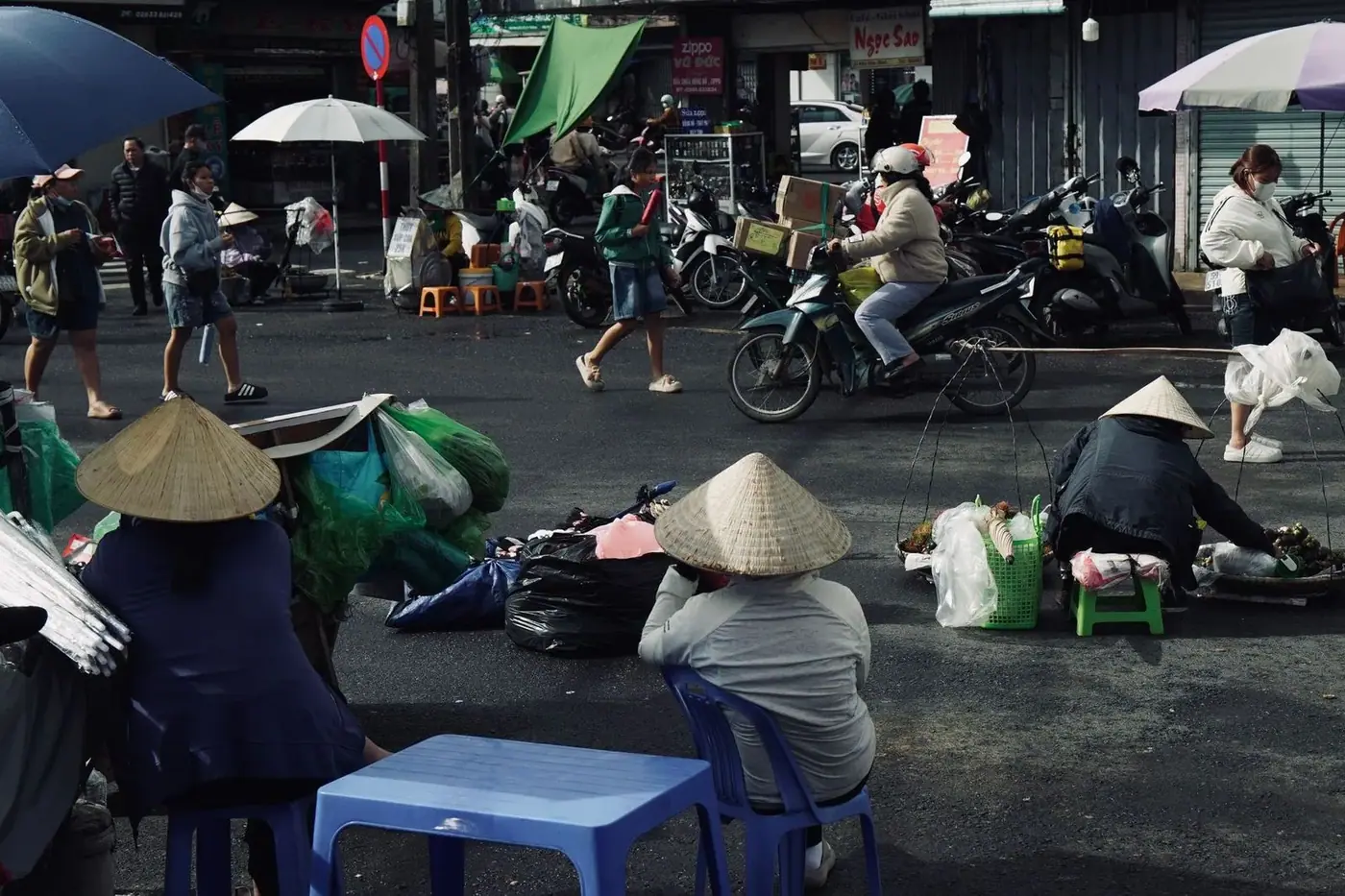 Street vendors wearing conical non la hats at a busy Vietnamese market