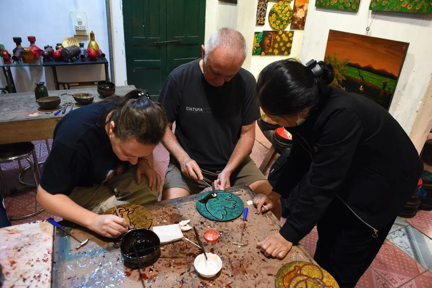 Artisans hand-painting traditional lacquerware pieces in a workshop