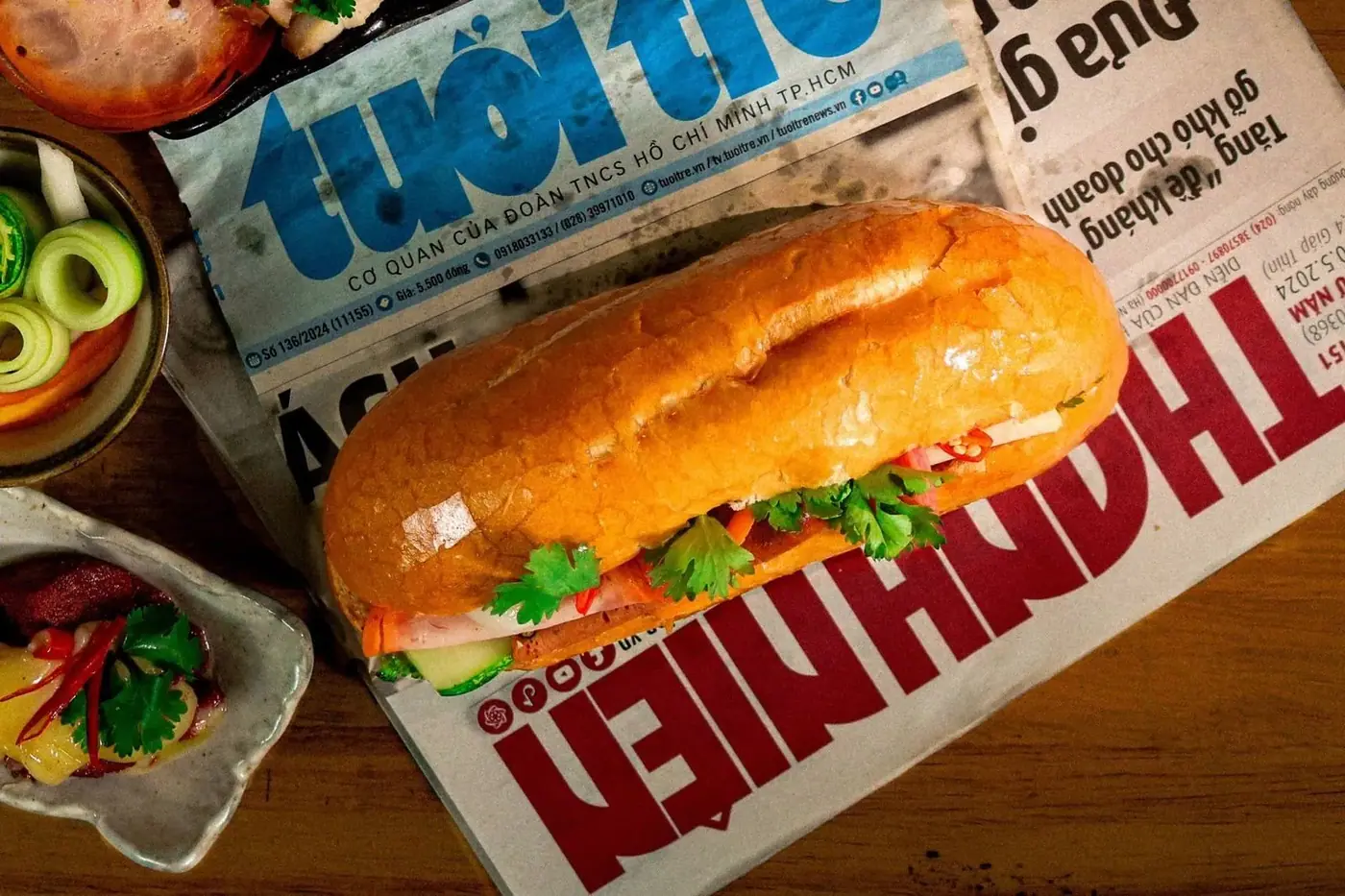 Vietnamese banh mi sandwich with pate, pickled vegetables and chili on newspaper