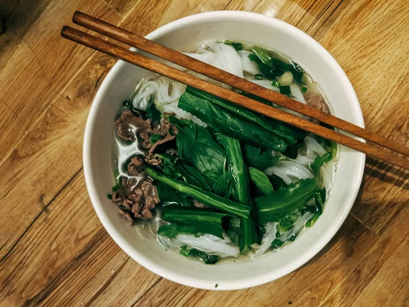 Bowl of Vietnamese pho with beef, herbs and chopsticks