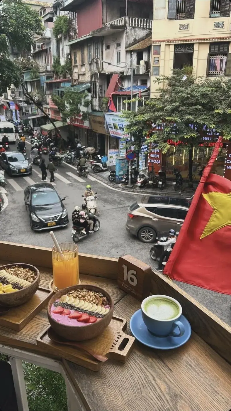 food and drinks on a table in front of a city street with cars, motorcycles and people
