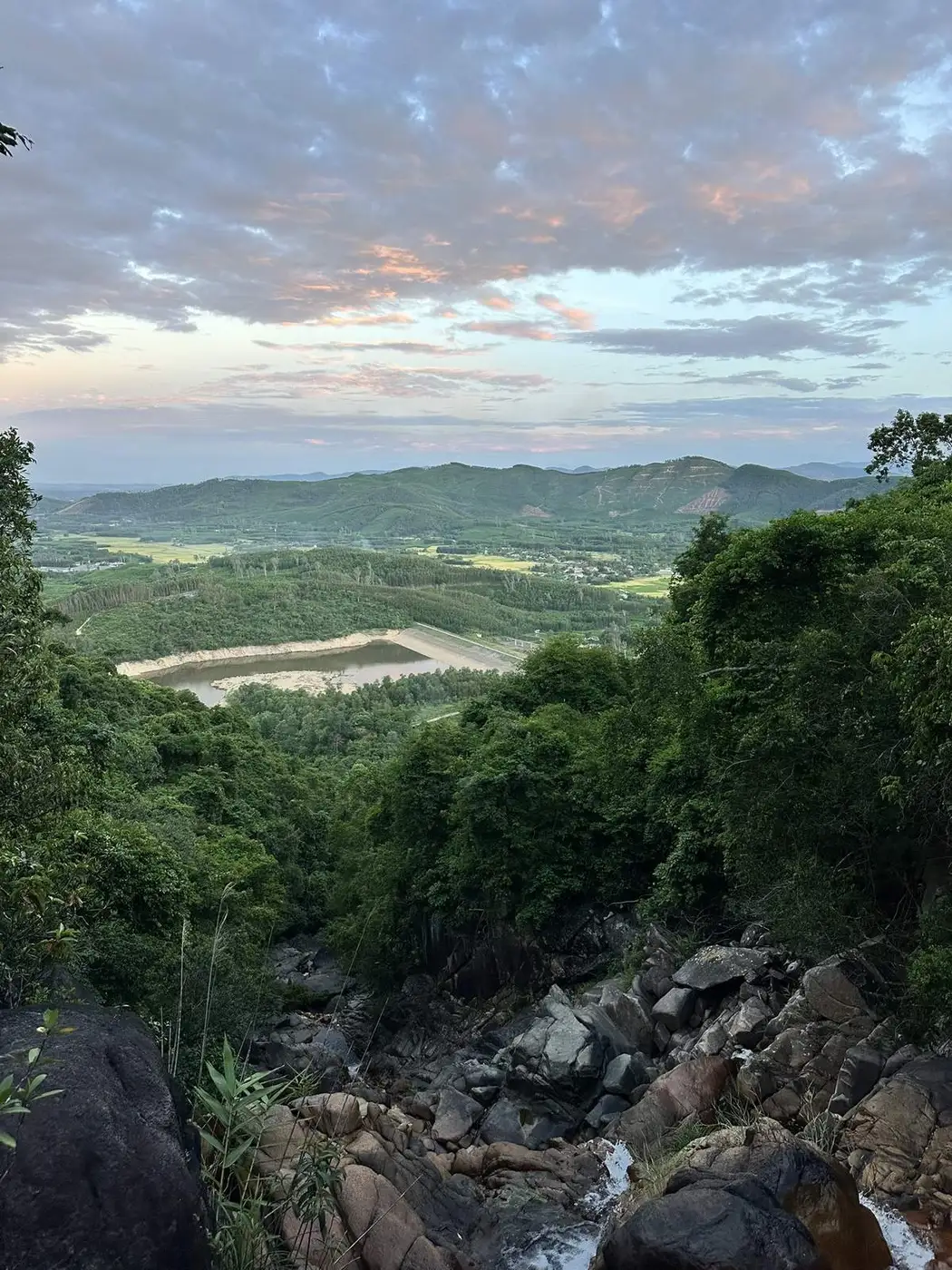 Green valley and reservoir seen from a hill at sunset