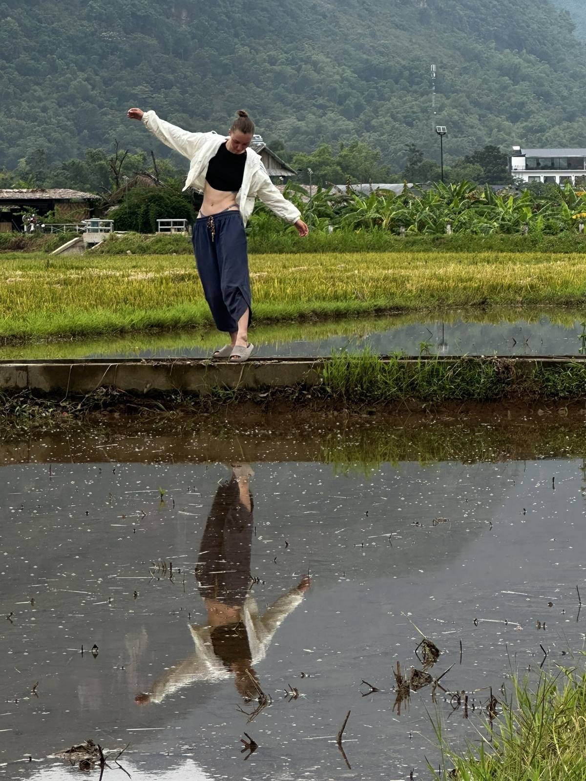 Traveler balancing on a dyke in a Vietnamese rice paddy
