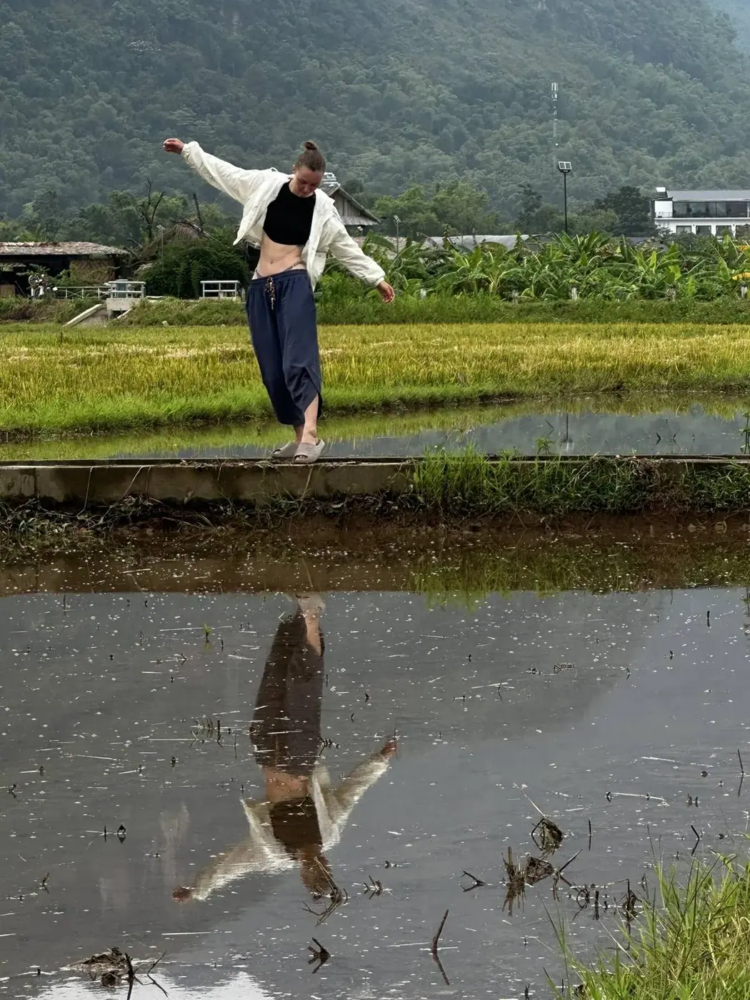 Traveler balancing on a dyke in a Vietnamese rice paddy