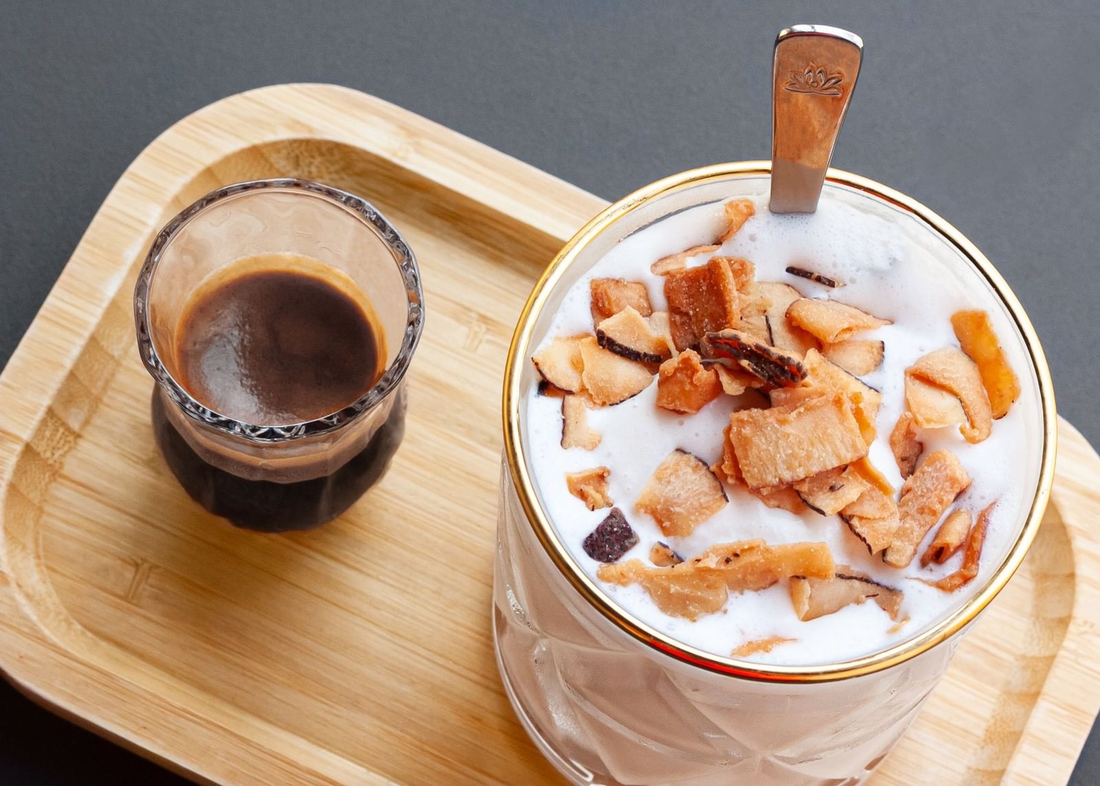 Coconut coffee topped with toasted coconut flakes next to a shot of black Vietnamese coffee