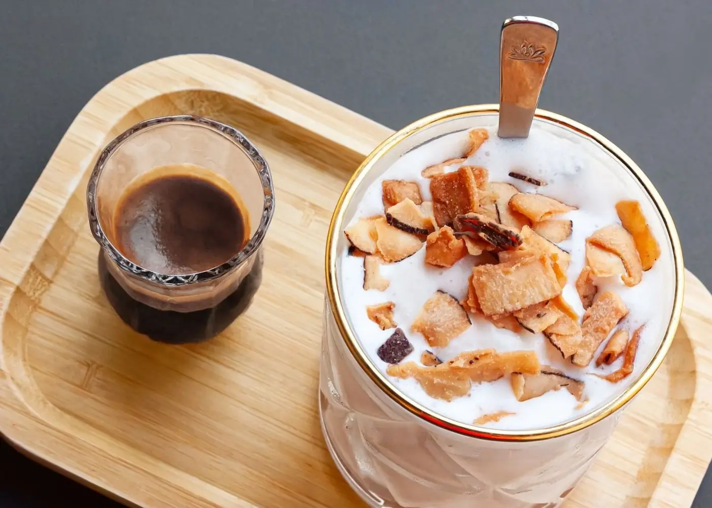 Coconut coffee topped with toasted coconut flakes next to a shot of black Vietnamese coffee