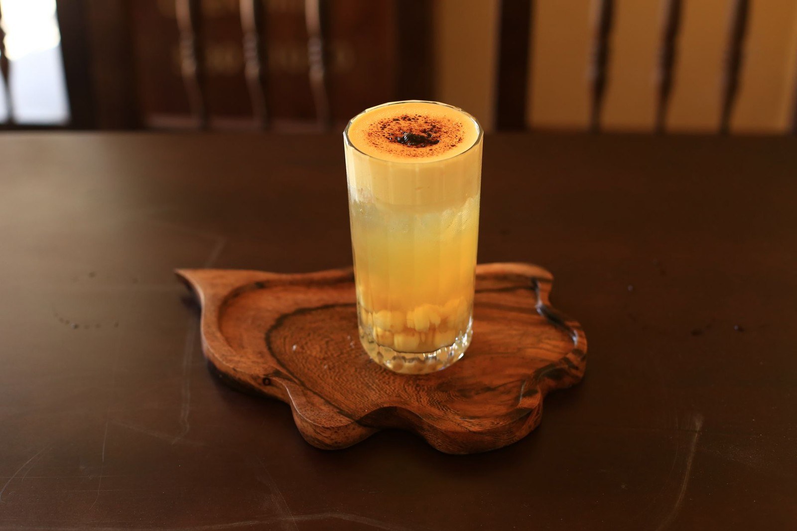Tall glass of Vietnamese egg coffee with whipped egg-yolk foam and cocoa dusting