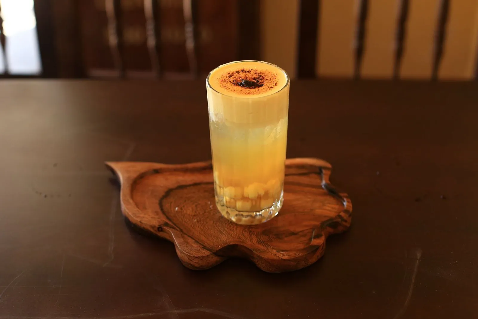 Tall glass of Vietnamese egg coffee with whipped egg-yolk foam and cocoa dusting