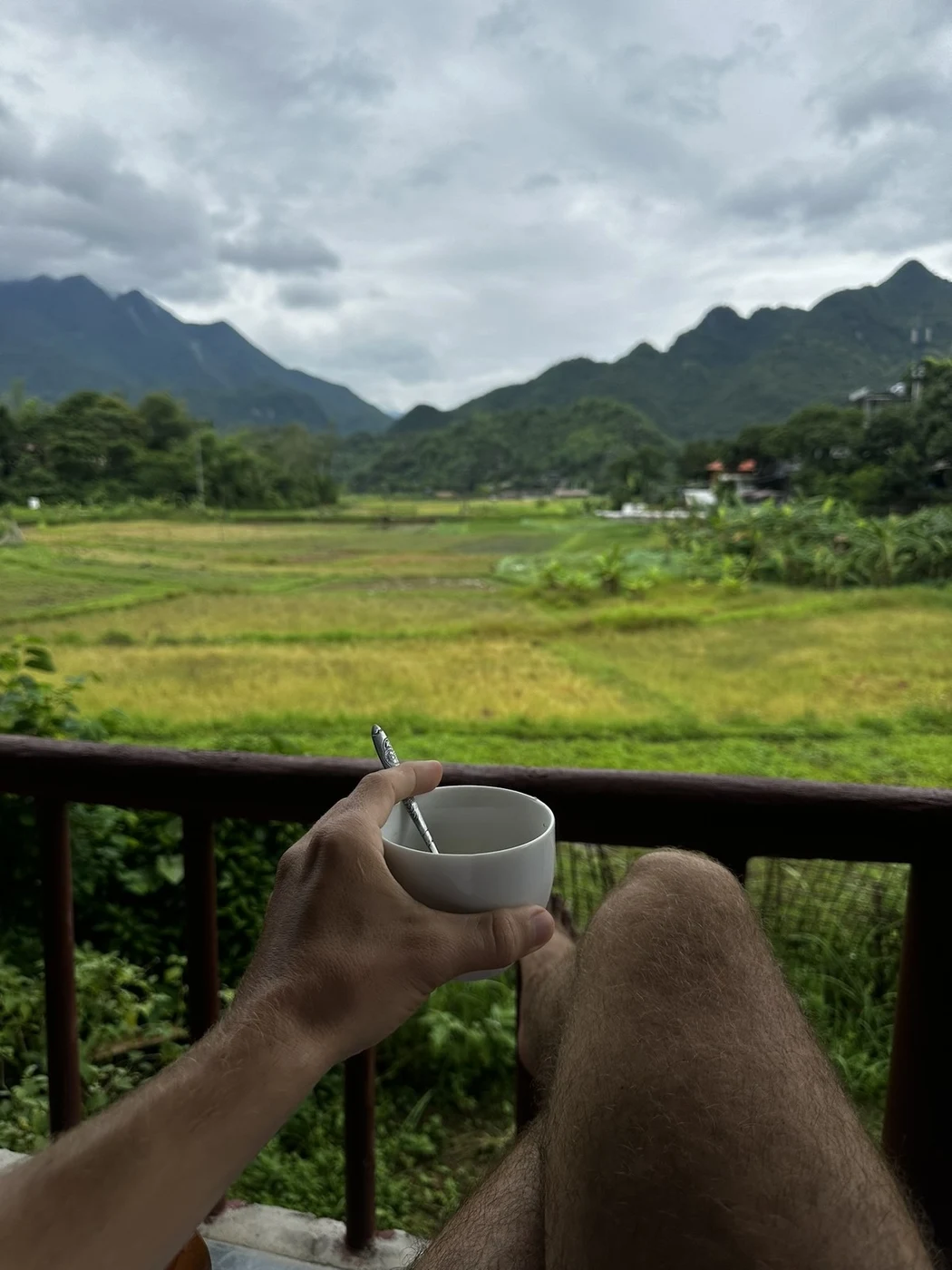 Cup of coffee on a café table with rice fields and limestone peaks of Ninh Binh behind