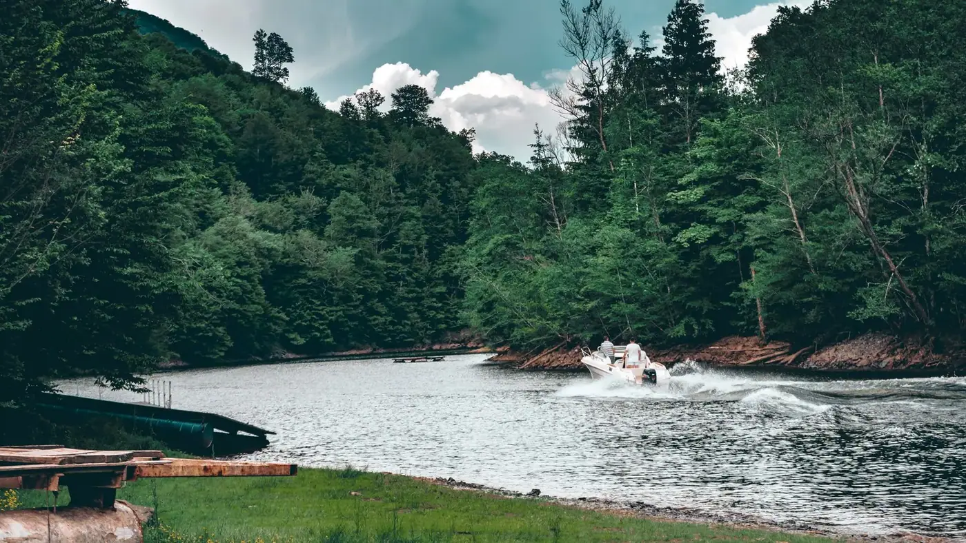 Boat gliding through a calm tropical river past green forest