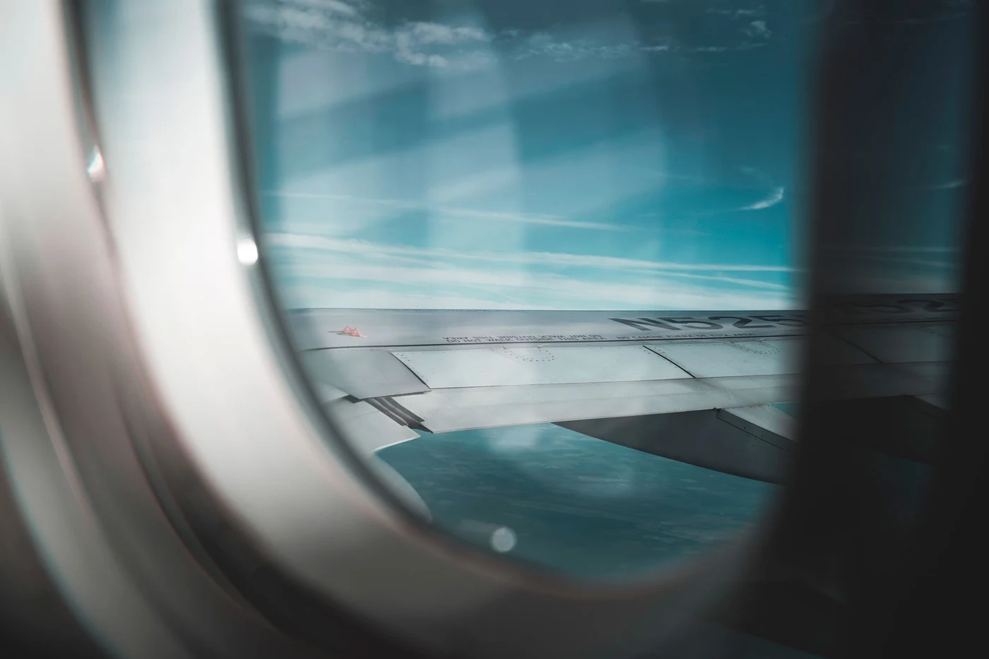 Airplane wing against blue sky seen from a window seat