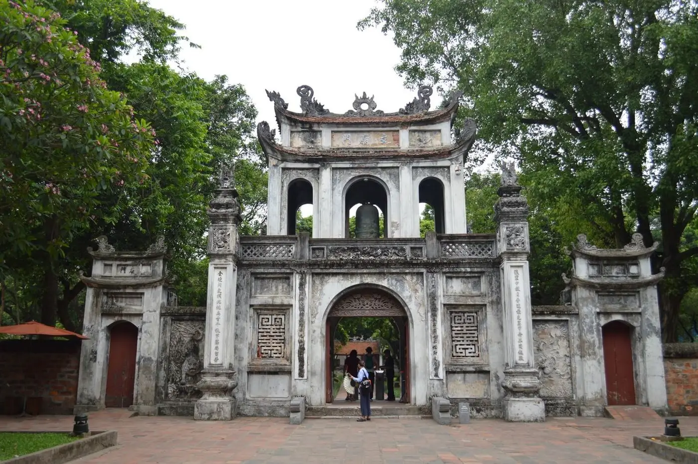Stone entrance gate of the Temple of Literature framed by trees