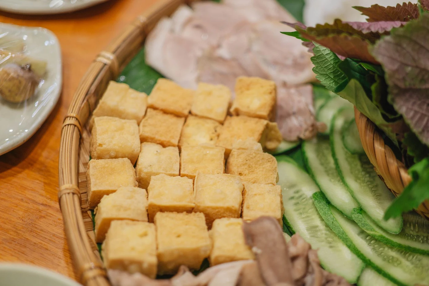 Vietnamese plate with tofu, vegetables and herbs on a wooden table