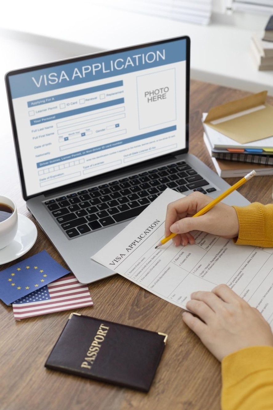 Visa application form on a laptop with paper application and passport
